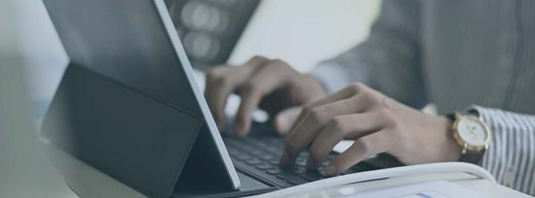 Fingers typing out a resume objective on a silver laptop.