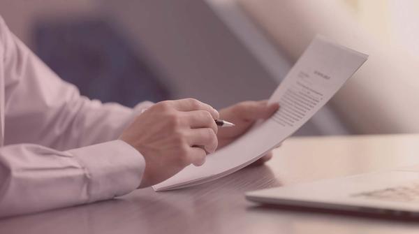 Hands holding a professional resume at an offic desk.