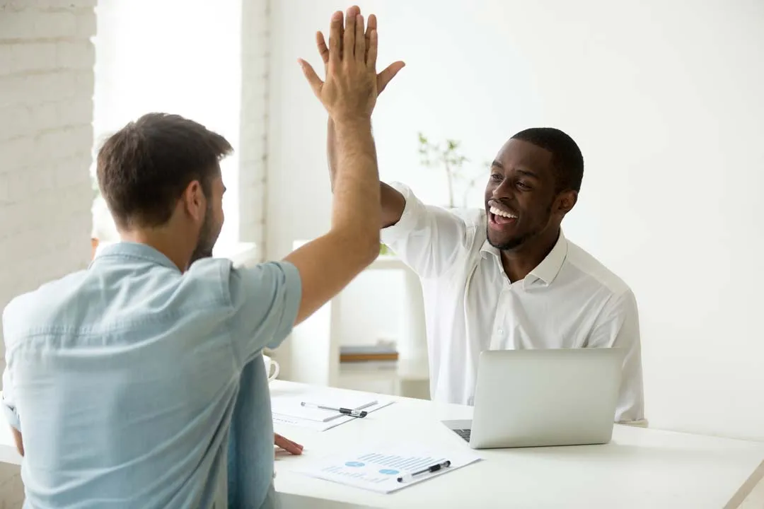 Two men at work sharing a high five, discussing a resume picture.