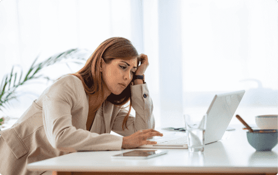 Frustrated woman stares at a blank laptop page instead of using cover letter examples.